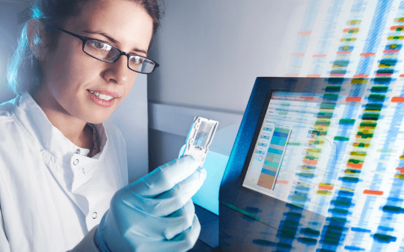 Laboratuvarda bilim insanı gen analizi yapıyor, arka planda DNA grafik verileri var